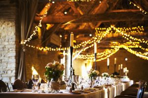 A wedding venue decorated for a party, with fairy lights and the tables set for dinner.