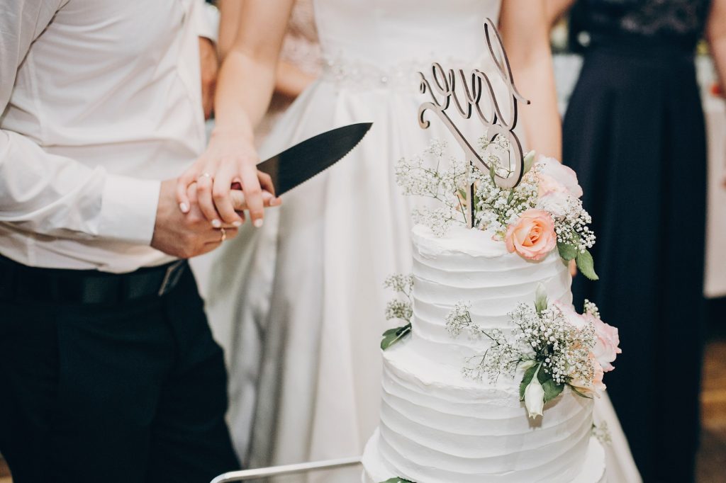 Bride and groom cutting stylish wedding cake at wedding reception